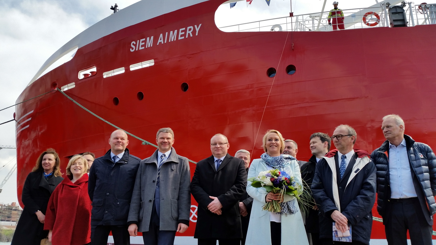 Przedstawiciele armatora i stoczni z matką chrzestną i statkiem w tle